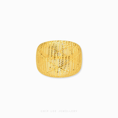 A chunky gold bangle bracelet with a textured, vertically ribbed openwork pattern, shown on a clean white background with a subtle drop shadow.