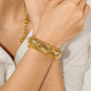 A close-up of a model's wrist wearing a chunky, textured gold bangle bracelet, with a matching gold chain necklace partially visible. The model is wearing a white top, and a faint 'CHIP LEE JEWELLERY' watermark is visible at the bottom.