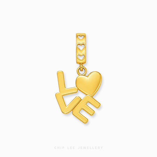 A gold-plated charm featuring the word 'LOVE' with a heart, shown on a clean white background with a brand watermark at the bottom.