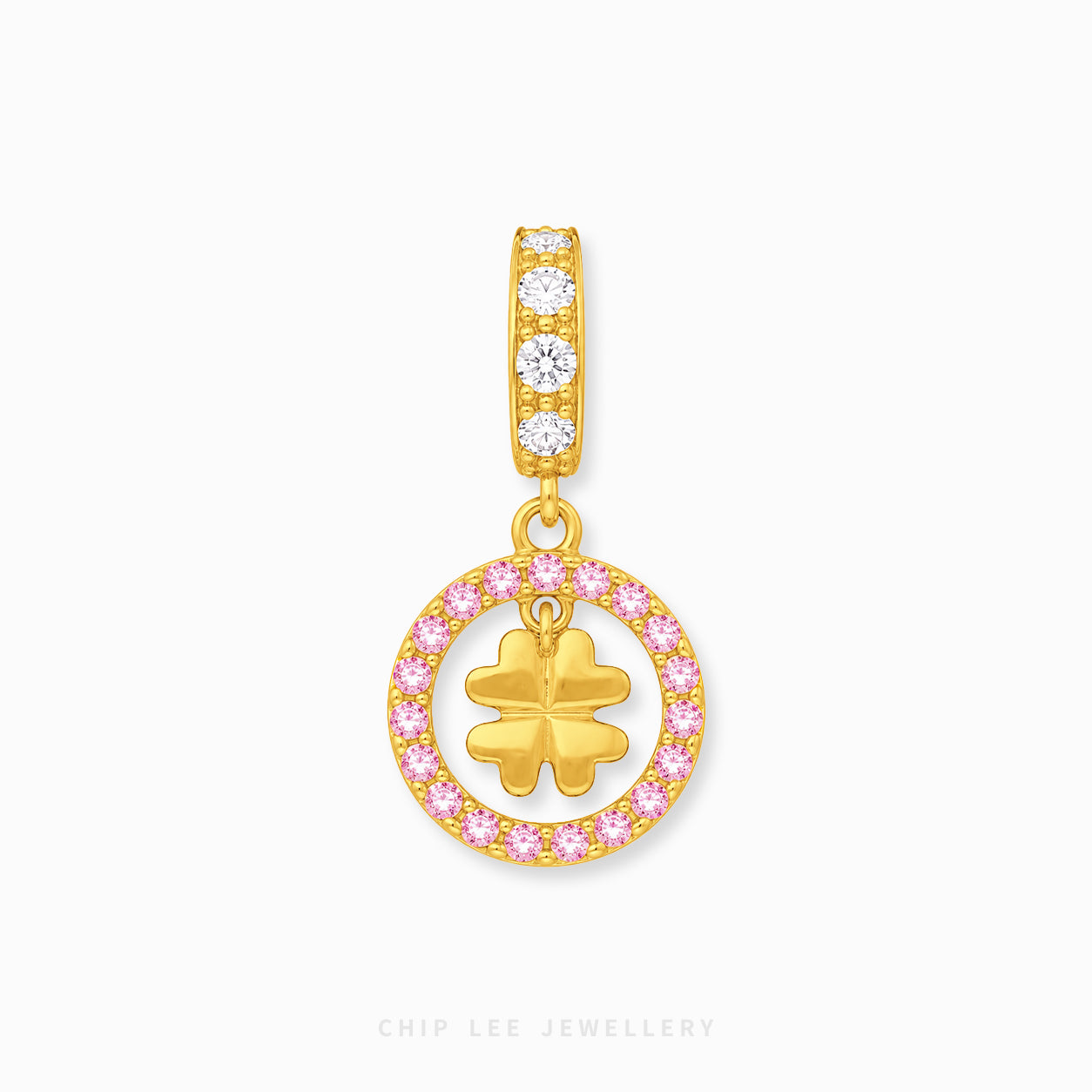 A gold charm pendant featuring a vertical bar with three clear stones and a dangling circular charm outlined in pink stones, with a gold four-leaf clover in the center, shown on a light gray background.