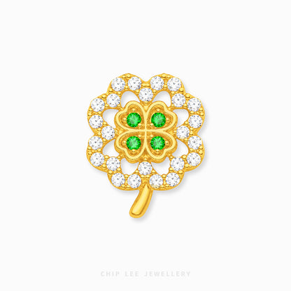 A gold four-leaf clover charm with four green gemstones in the center and a border of clear cubic zirconia stones, shown on a light gray background with a Chip Lee Jewellery watermark.