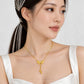 Lyla necklace featuring a rounded ribbon bow pendant with intricate openwork loops and two dangling gold beads