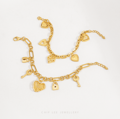 Gold charm bracelet with heart and key designs on a white background