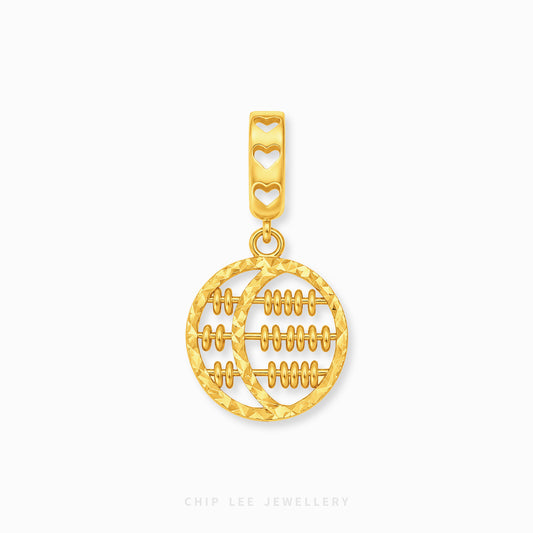 A gold pendant charm featuring a circular design with horizontal lines resembling a traditional abacus, suspended from a bail decorated with three heart cutouts, shown on a light gray background.