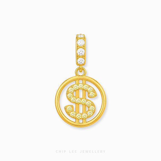 A gold pendant featuring a circular openwork design with a dollar sign motif, embellished with small clear stones, and a top bail with four clear stones, shown on a light gray background.