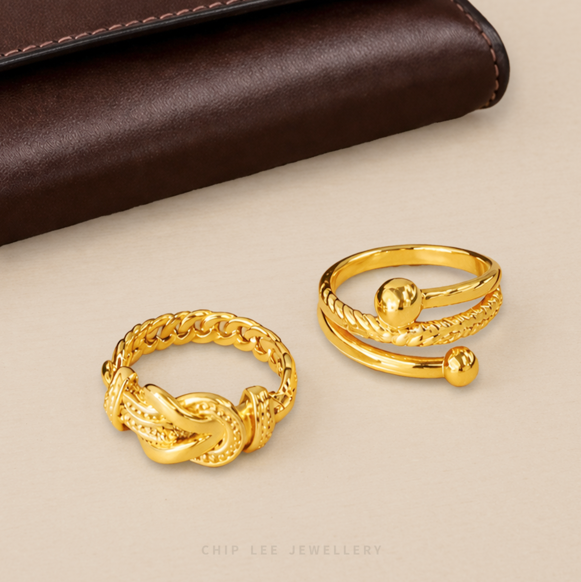 Two gold rings on a beige surface with a brown leather background