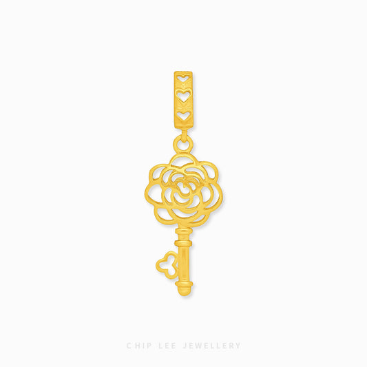 A 916 gold key-shaped charm with floral design details.