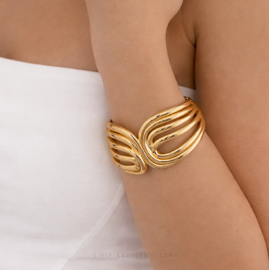 Gold bracelet on a person's wrist with a plain background