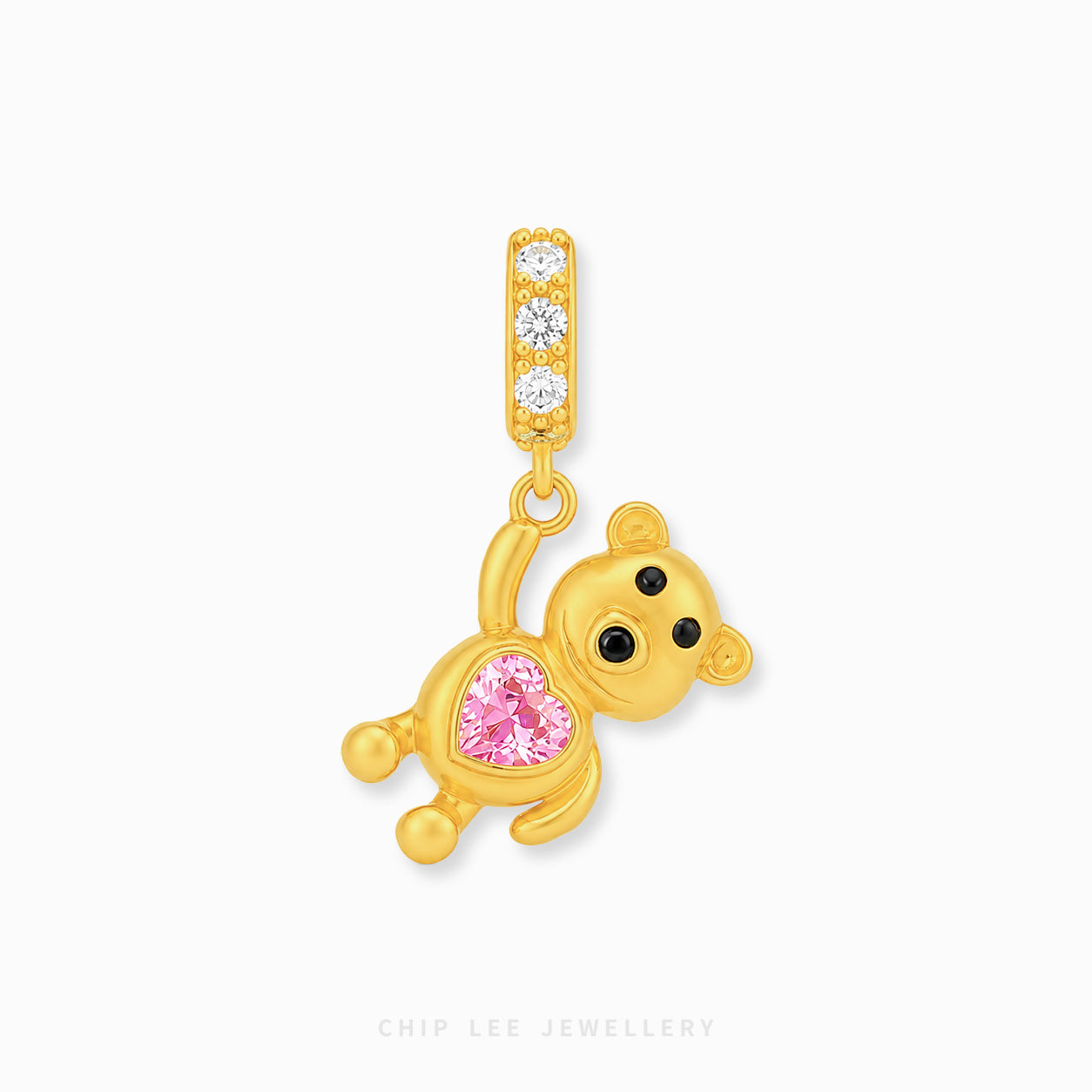 A gold teddy bear charm pendant with a pink heart-shaped crystal on its belly, hanging from a gold bar with three clear crystals, shown on a light gray background.
