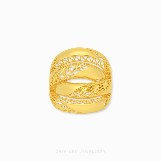 A gold ring with an intricate, openwork filigree design and a central floral motif, shown on a clean white background with a brand watermark at the bottom.