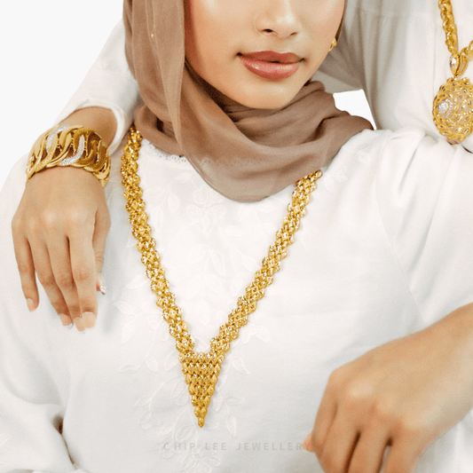 Woman wearing a gold necklace and bracelet on a white background