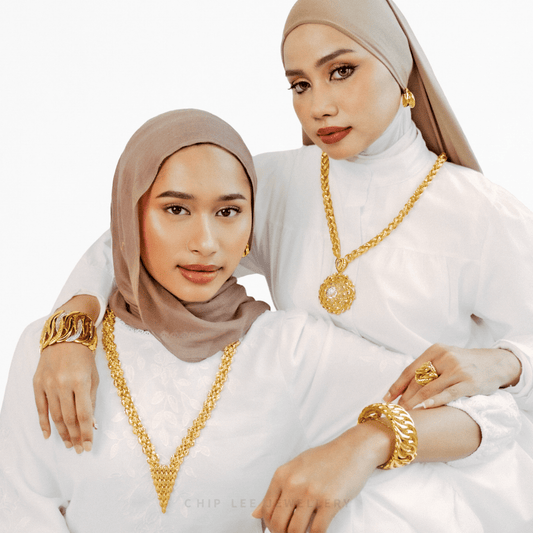 Two women wearing gold jewelry against a white background