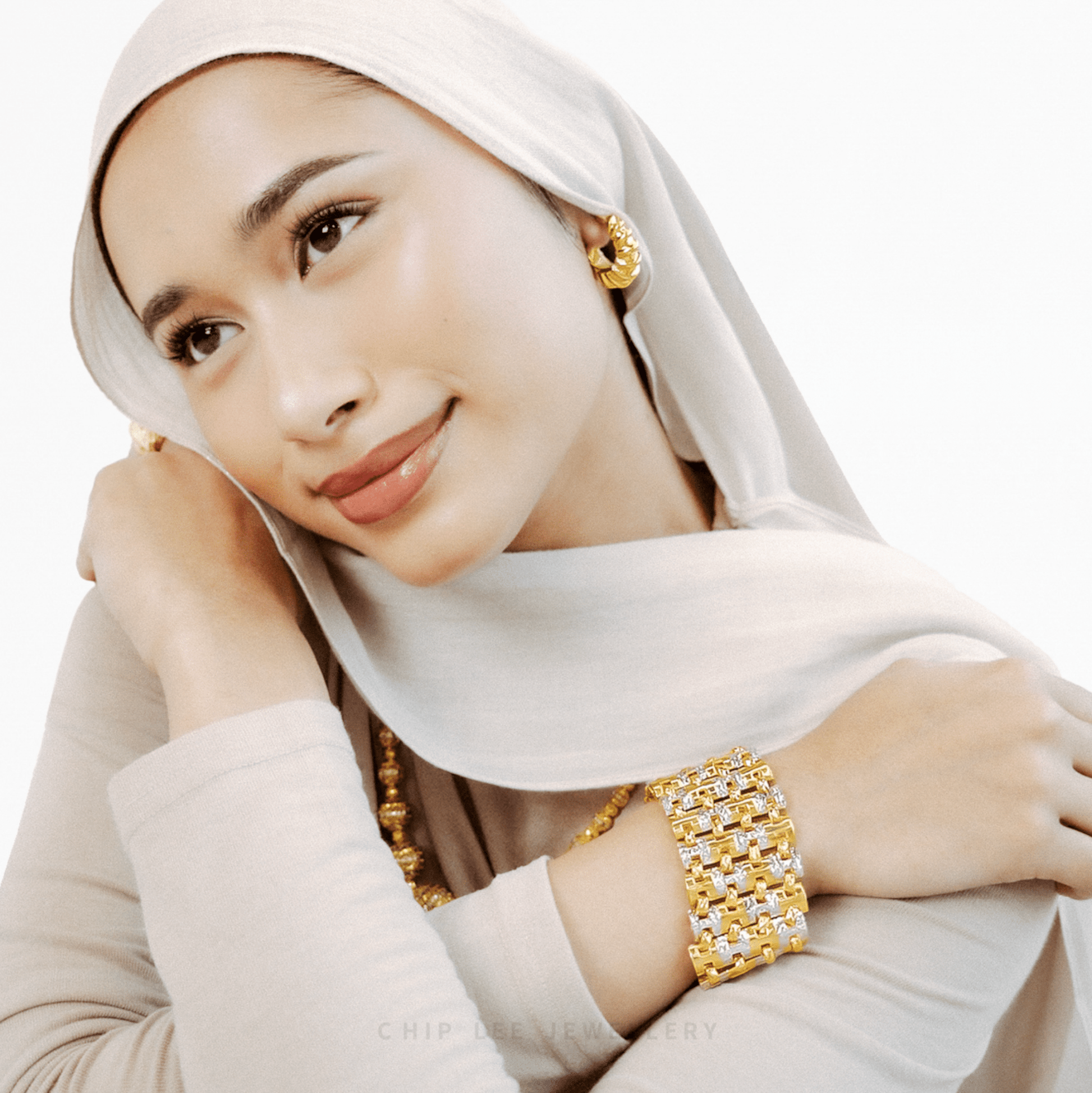 Woman wearing gold jewellery with a white hijab on a white background