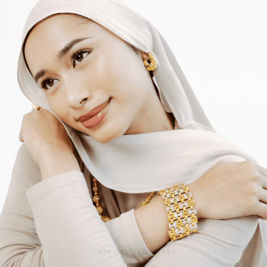 Woman wearing gold jewellery with a white hijab on a white background