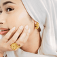 Woman wearing gold earrings and ring, with a soft focus on the jewellery.